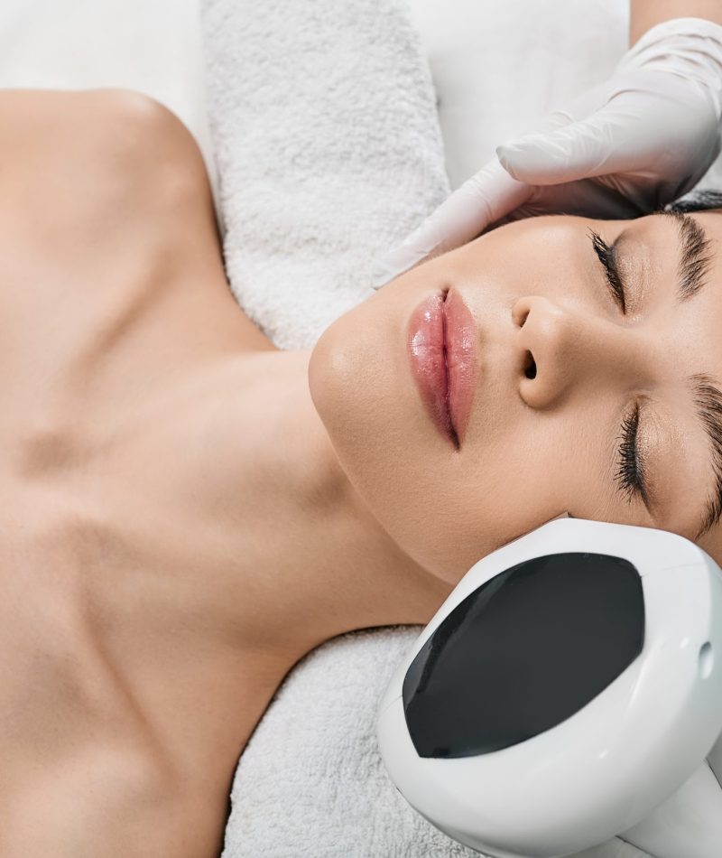 Woman receiving IPL procedure for her face at a beauty center to remove brown spots and treat rosacea. Facial Rejuvenation with intense pulsed light apparatus